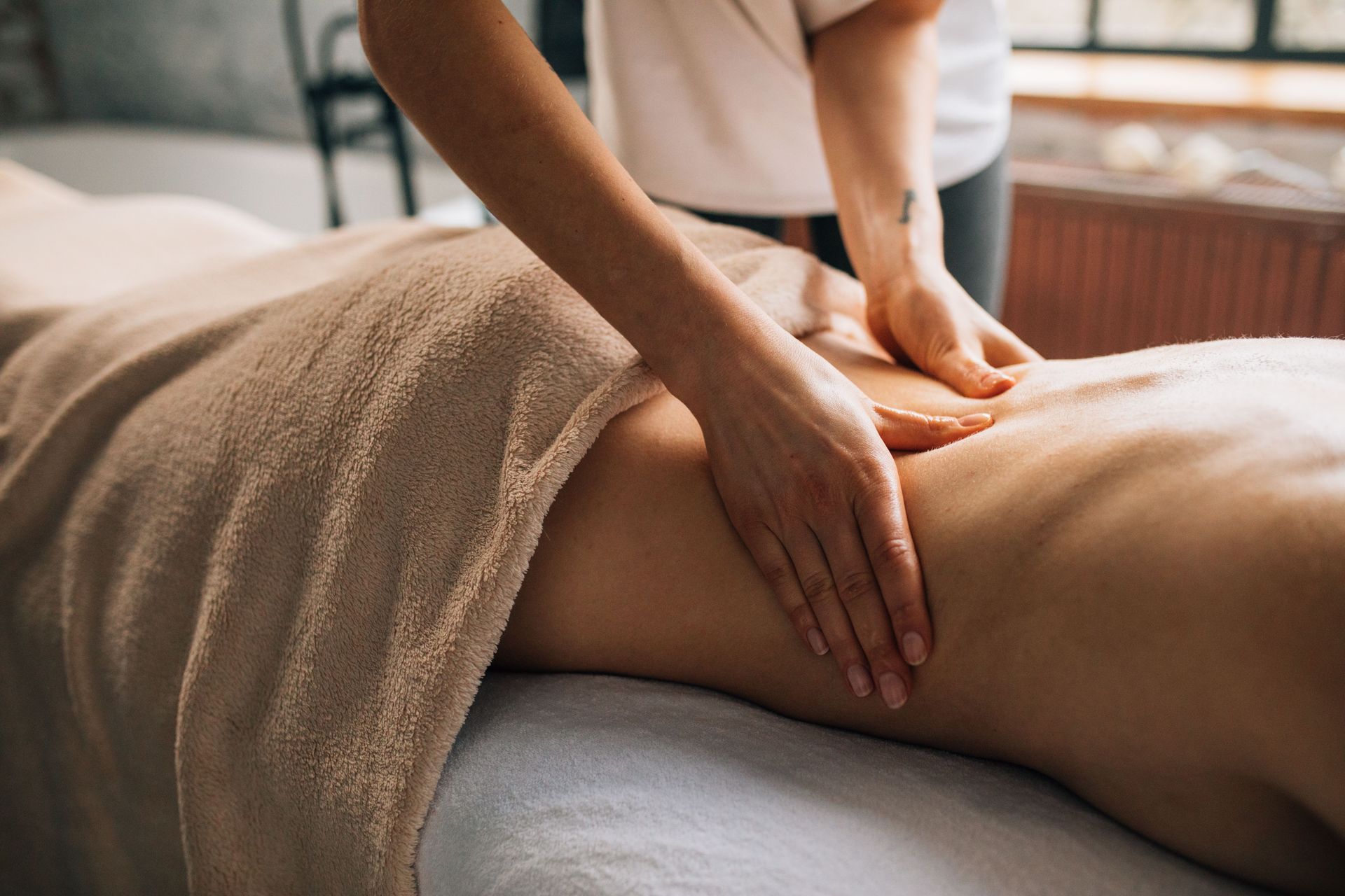 A serene massage session indoors highlighting hands-on body care and relaxation.